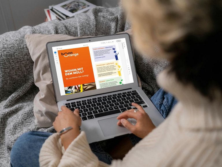 Person am Laprop, auf dem das Faltblatt "Wohin mit dem Müll?" von bonnorange geöffnet ist.