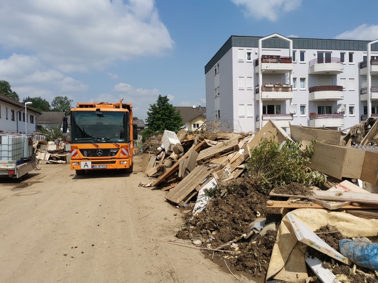 bonnorange im Hochwasser-Einsatz in Sinzig Abfallsammelfahrzeug der bonnorange AöR in einer Straße in Sinzig, die mit Abfällen, die durch das Hochwasser entstanden sind, gesäumt ist.