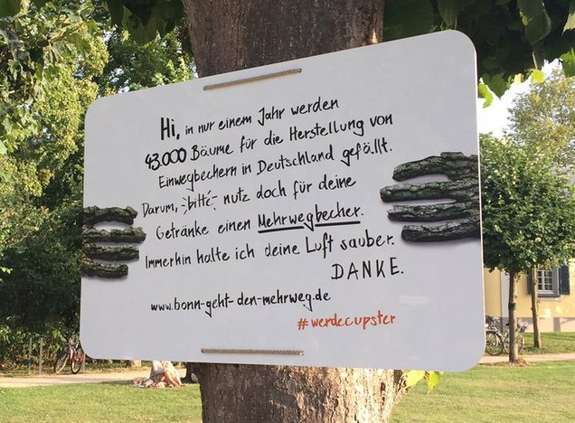 Schild hängt an einem Baum, auf dem ein Text steht, der auf die Ressource Baum einzahlt