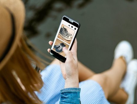 Frau mit Smartphone, auf dem eine Second-Hand-Shopping-App geöffnet ist.