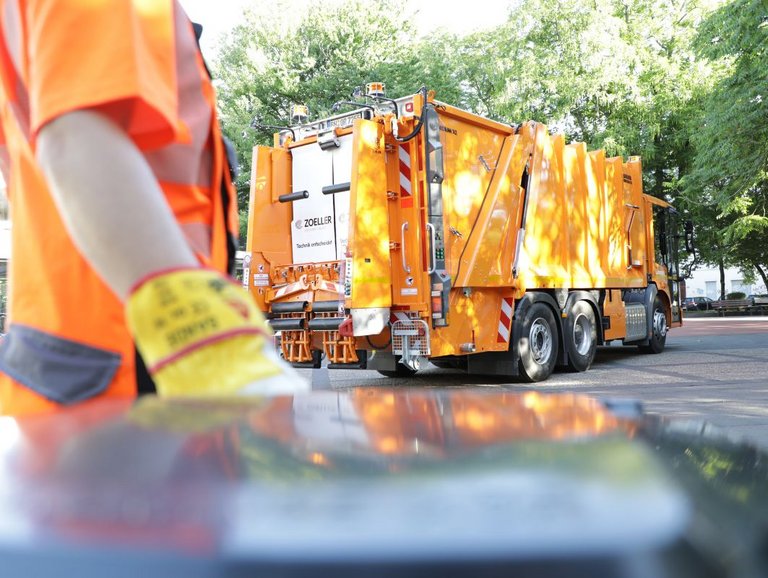 Müllwerker von bonnorange zieht eine Mülltonne zum Fahrzeug