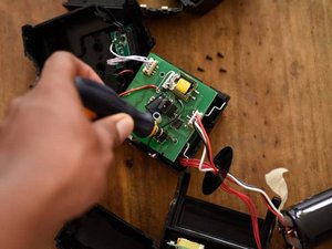 Ein Elektrogeraet ist in seine Kleinteile gelegt und wird repariert. 