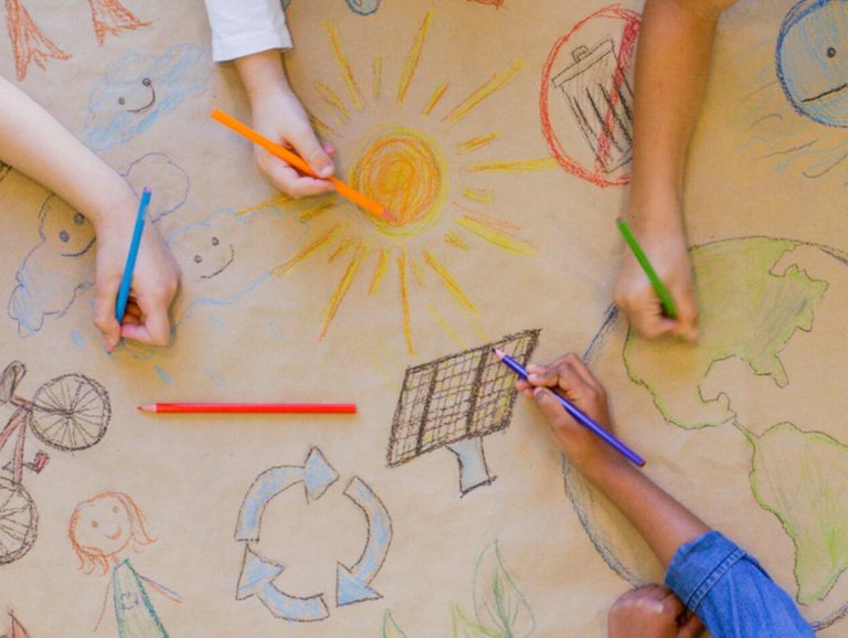 Zu sehen ist ein Tisch, an dem Kinder verschiedene Symbole aufzeichnen.