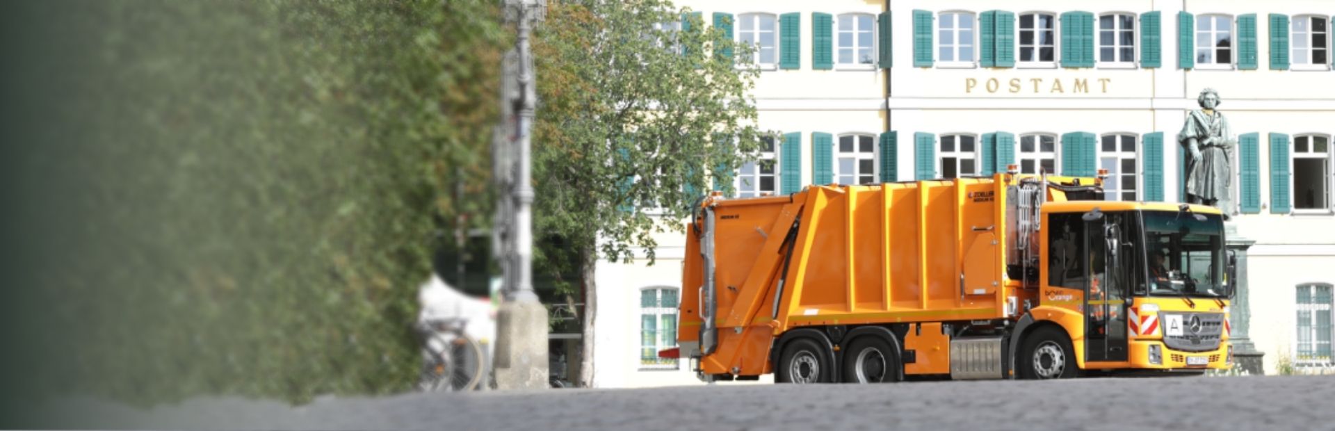 Waste collection vehicle in front of the Old Post Office with the Beethoven monument in Bonn